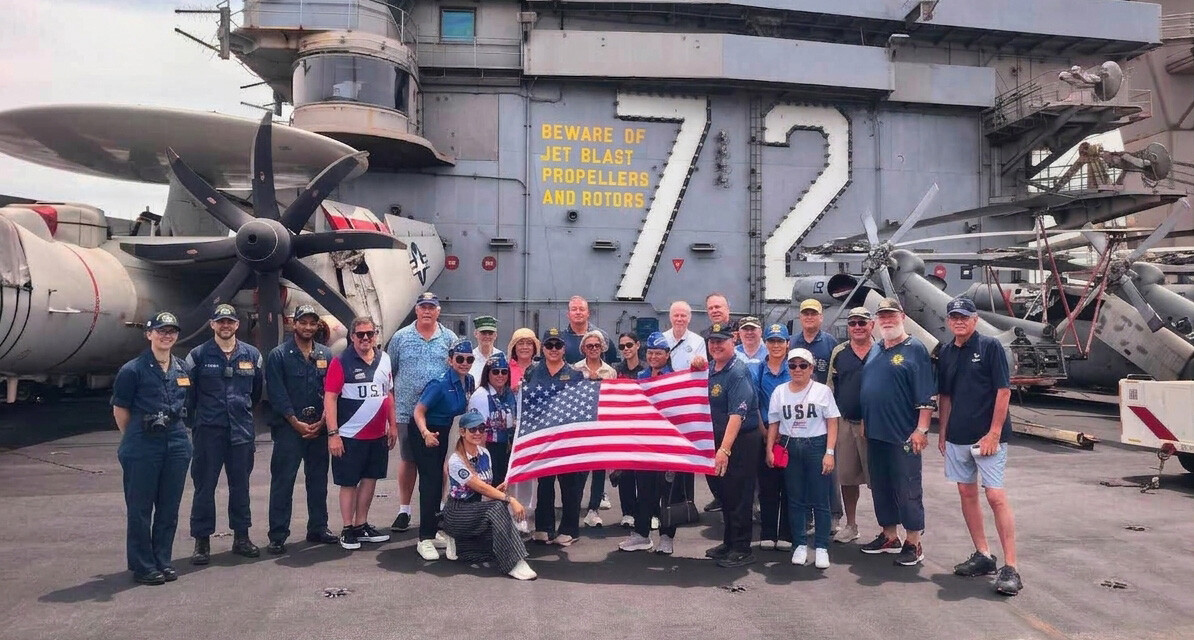 A group of visitors poses on the deck of USS Abraham Lincoln. (Photo via Michael J. Chitwood)