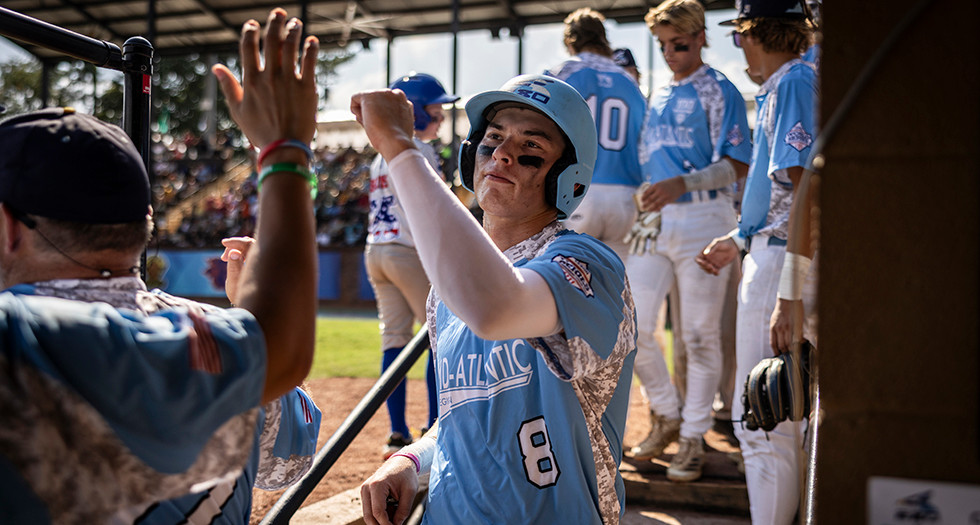 Keegan Haesler of Chesapeake, Va. Post 280 is congratulated by his teammates after scoring a run during Game 7 of the 2025 American Legion World Series. Photo by Chet Strange